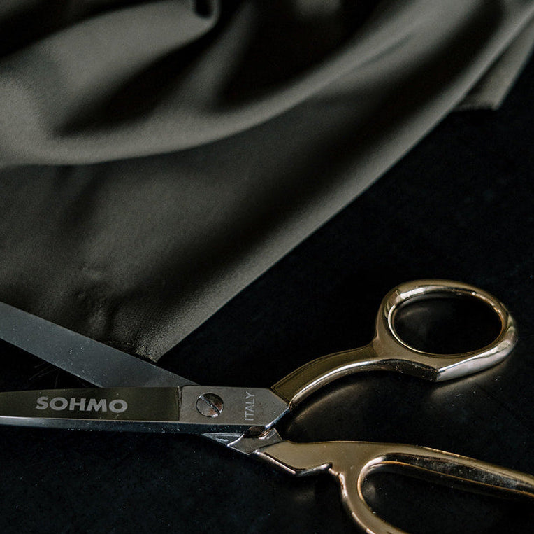 Pair of scissors with 'Soho' branding on a dark fabric background
