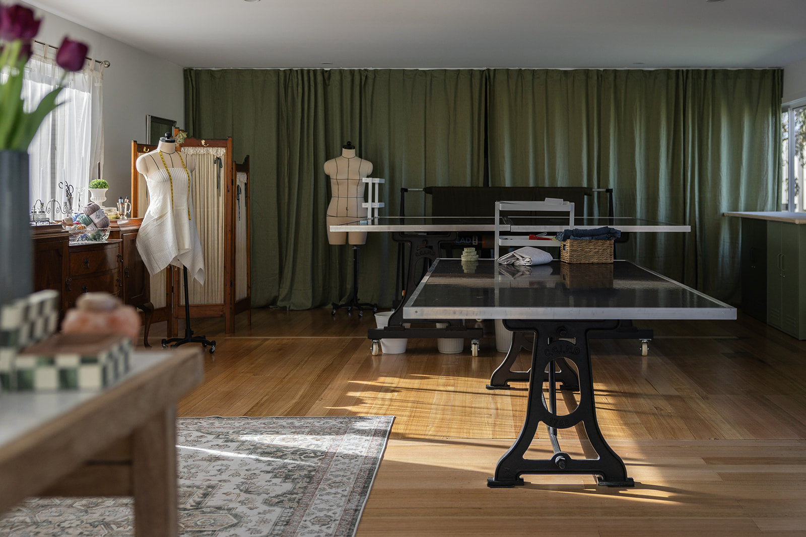 Room with a ping pong table, green curtains, and various items on a shelf.
